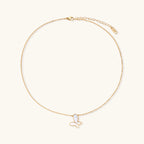 Gold-plated butterfly pendant with iridescent mother of pearl inlay on delicate chain against cream background.