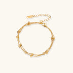 Three-strand gold-plated bracelet with clustered ball beads and adjustable clasp on cream background