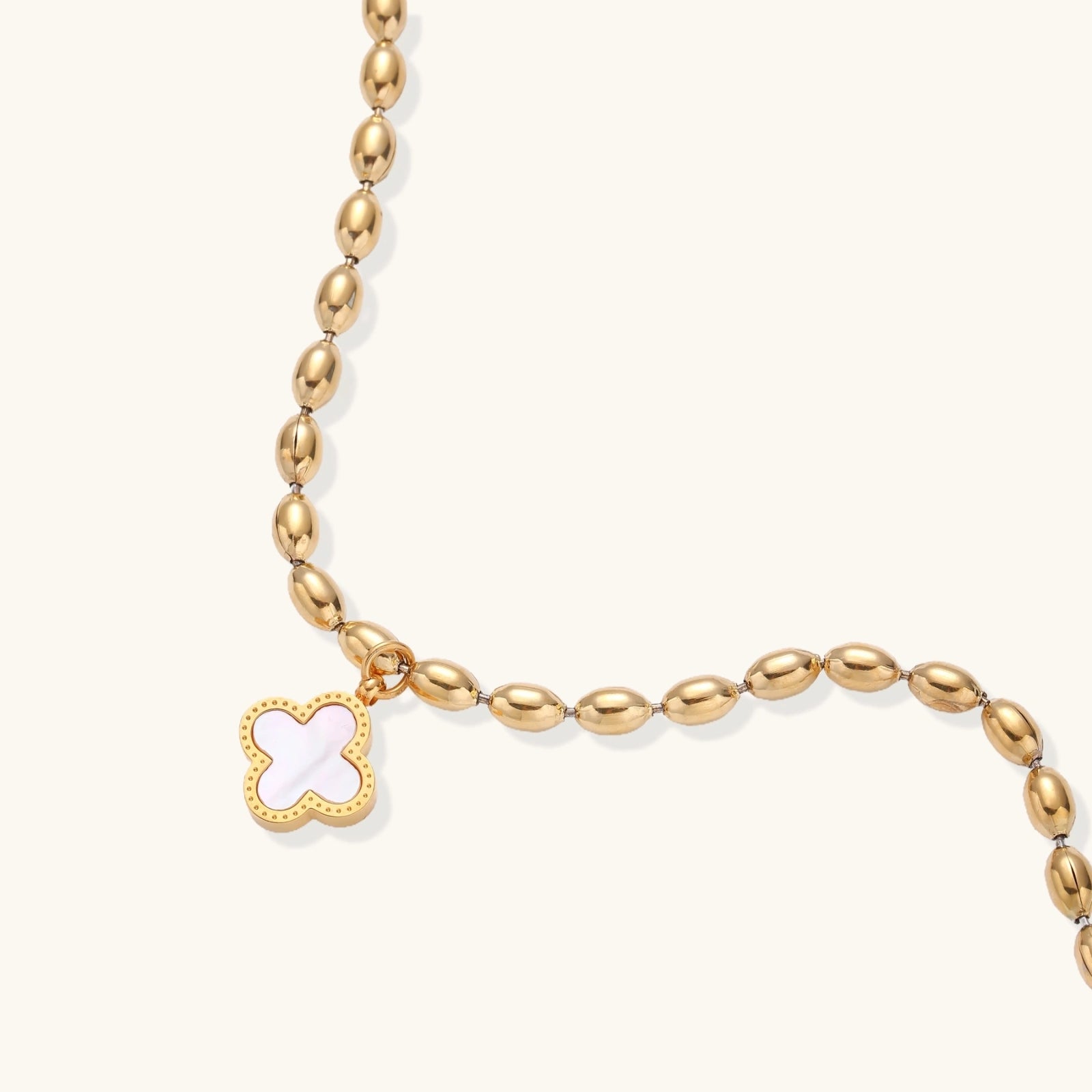 18K gold-plated oval bead bracelet with a four-leaf clover charm in mother-of-pearl or black enamel, adjustable lobster clasp, on white background.