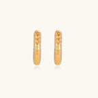 Gold-toned hoop earrings with hammered dimpled texture and post closure on cream background