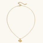 Layered necklace with green stone beads, gold spacers, white accents, and protective eye pendant on cream background.