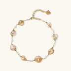 Gold-plated necklace with wire-wrapped shell pieces and freshwater pearls on neutral background, adjustable chain visible.