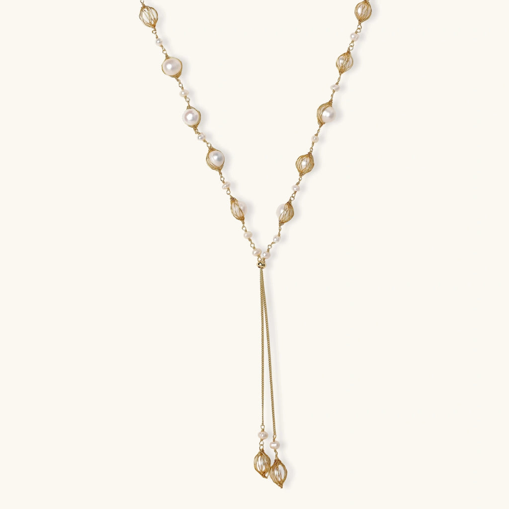 Adjustable gold lariat necklace with freshwater pearls nested in delicate cage settings and Y-shaped tassel drop