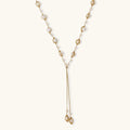Adjustable gold lariat necklace with freshwater pearls nested in delicate cage settings and Y-shaped tassel drop