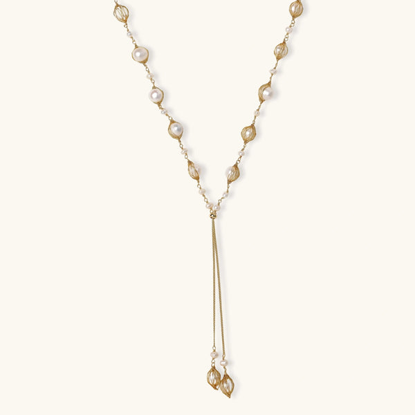 Adjustable gold lariat necklace with freshwater pearls nested in delicate cage settings and Y-shaped tassel drop