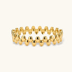 18K gold plated stainless steel bangle with dual rows of polished oval pebble beads on a cream background.