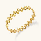 18K gold plated stainless steel bangle with dual rows of polished oval pebble beads on a cream background.