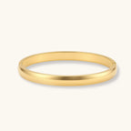 Polished 18K gold plated stainless steel hinge bangle with smooth flat-top profile on cream background.