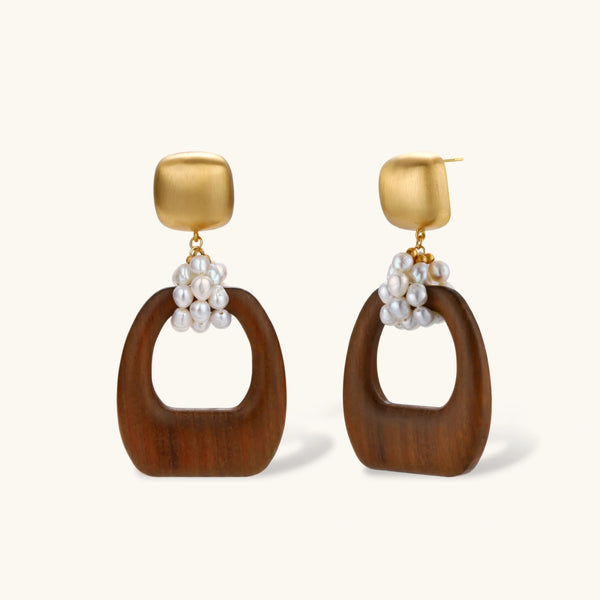 Gold-plated stud earrings with pearl clusters and organic brown wooden hoops on cream background