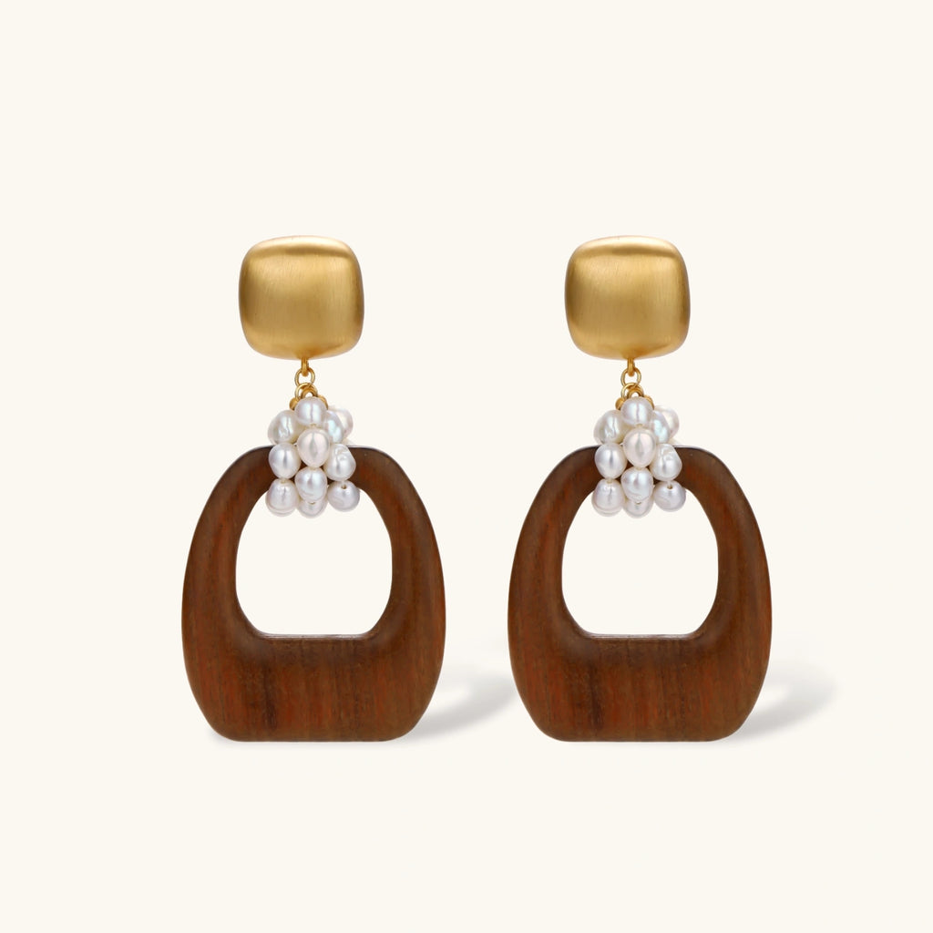 Gold-plated stud earrings with pearl clusters and organic brown wooden hoops on cream background