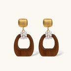 Gold-plated stud earrings with pearl clusters and organic brown wooden hoops on cream background