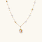 Delicate 18k gold-plated chain with baroque pearls and colorful enamel pendant featuring blue, pink accents on cream background.