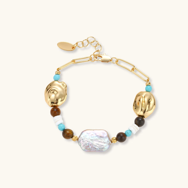 Gold-plated bracelet with baroque pearl centerpiece, turquoise and amber natural stones on adjustable chain against white background.