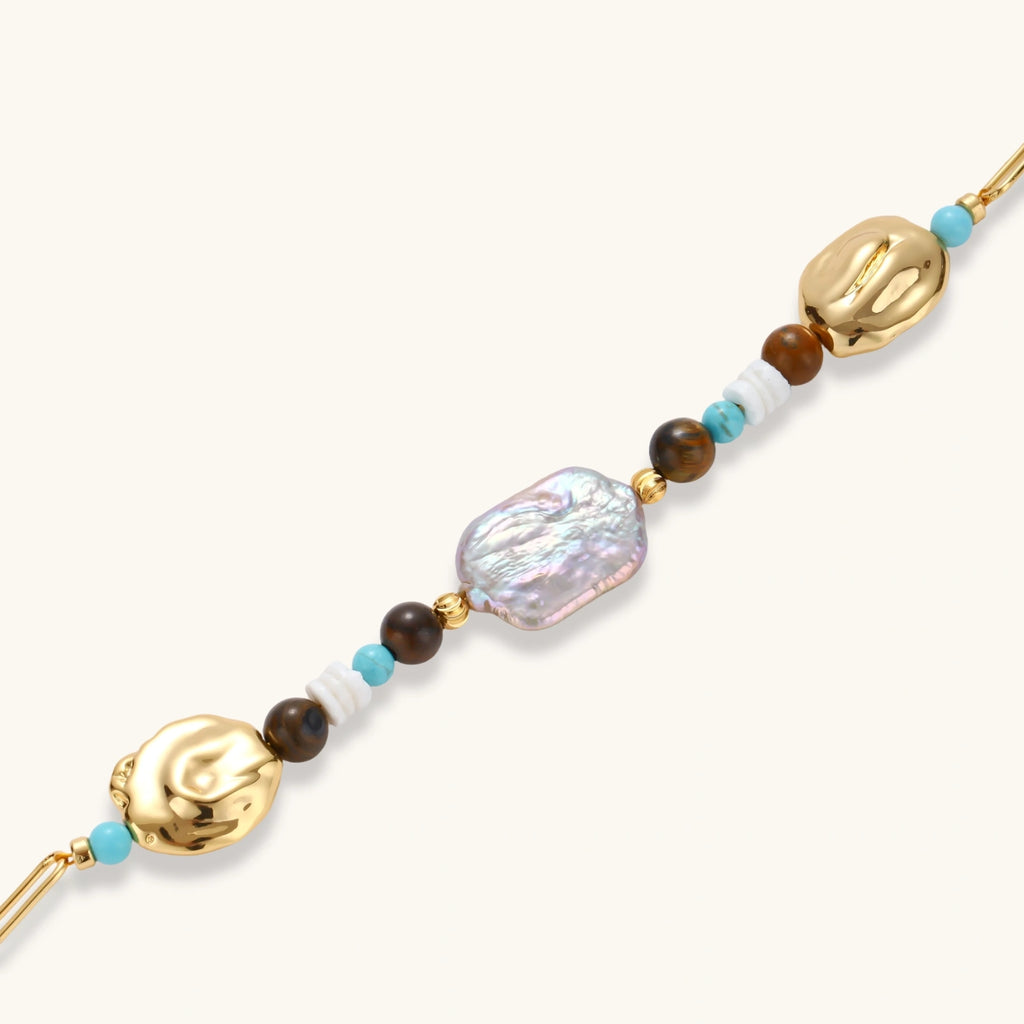 Gold-plated bracelet with baroque pearl centerpiece, turquoise and amber natural stones on adjustable chain against white background.