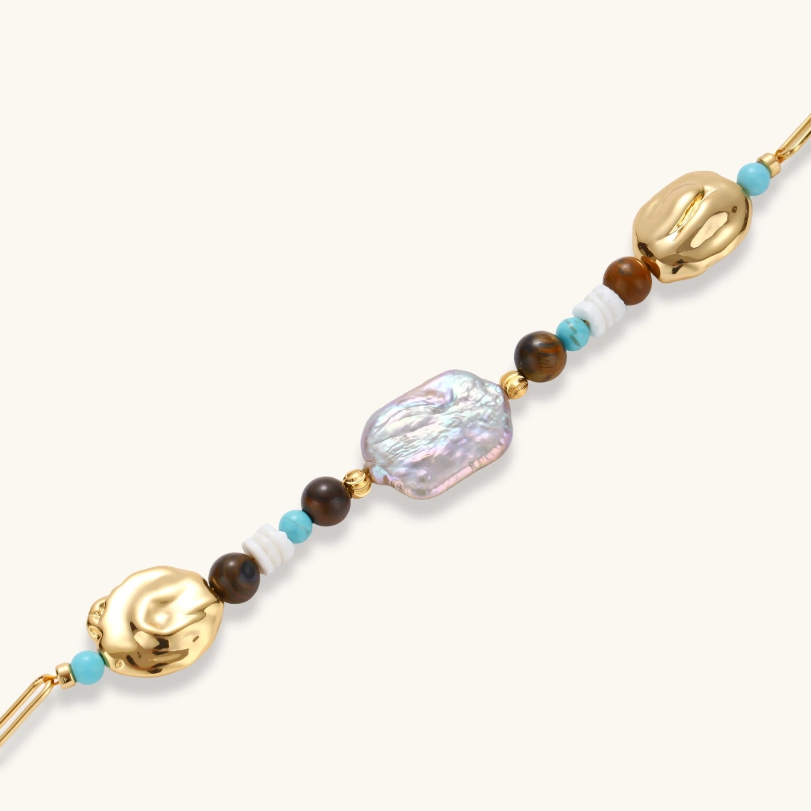 Gold-plated bracelet with baroque pearl centerpiece, turquoise and amber natural stones on adjustable chain against white background.